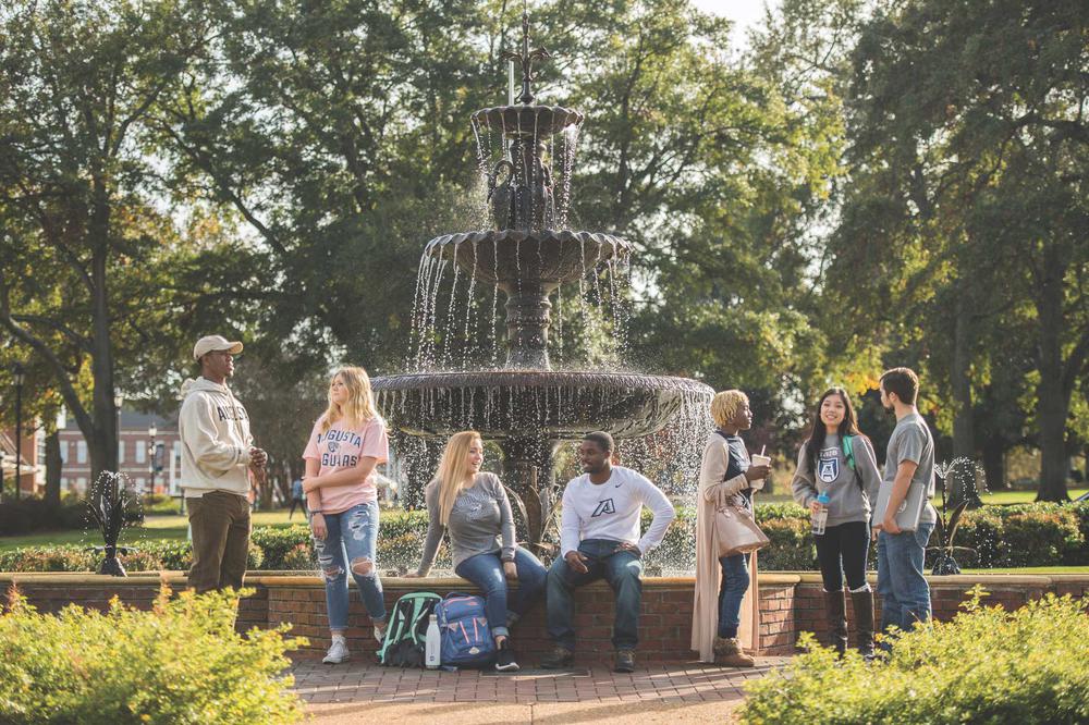 Augusta University students sitting next to fountain