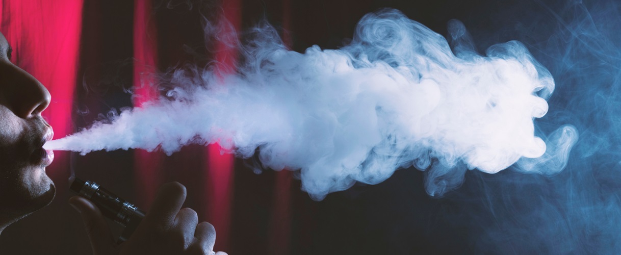 Man blowing vape smoke from the side