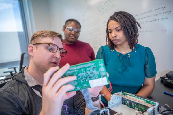 SCCS students and faculty looking at technical device