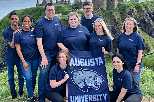 Group of people abroad holding an Augusta University flag