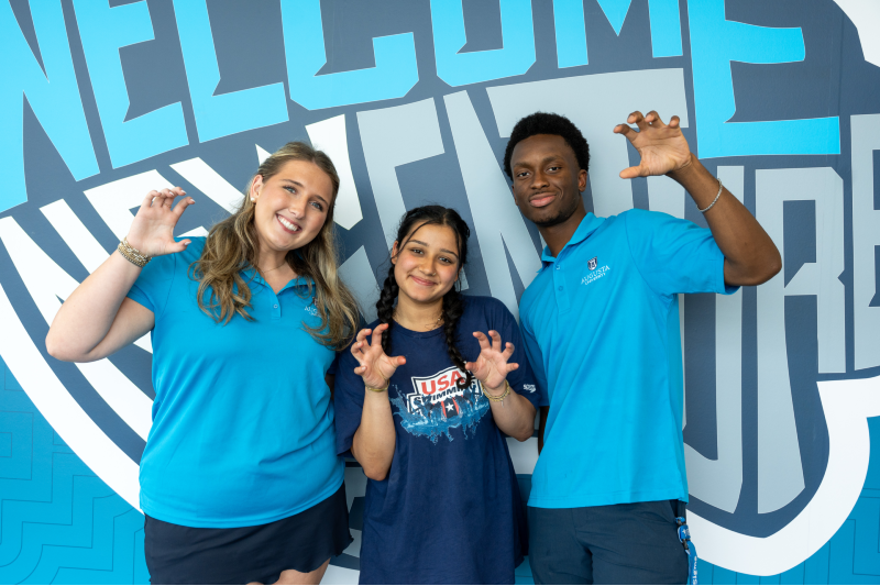 three students holding up a paw hand