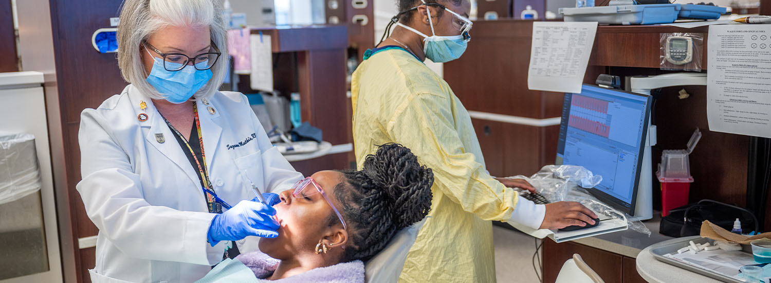 faculty helping with patient while student assists