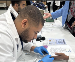 Person taking blood sample from the finger of a patient