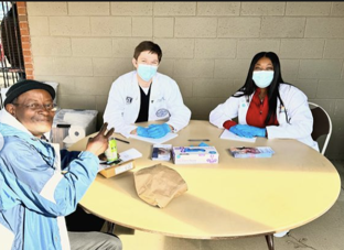 Students sitting with a happy patient at a table.