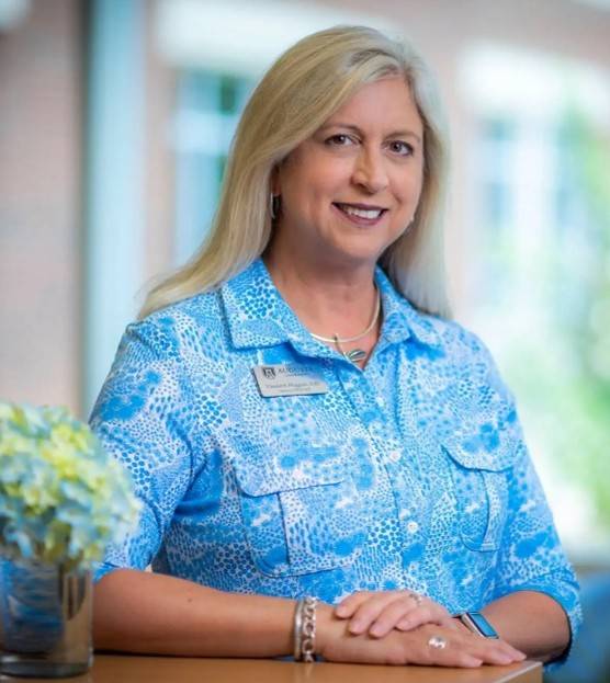 Beth Huggins woman wearing a blue top leans against a countertop
