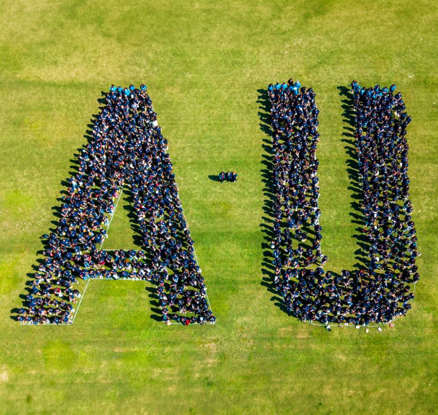 group of people gathered together inside white outlined A-U letters