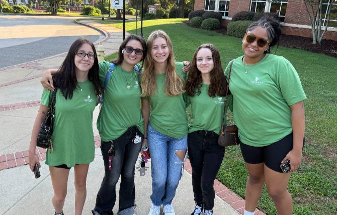 five girls in green shirts standing together