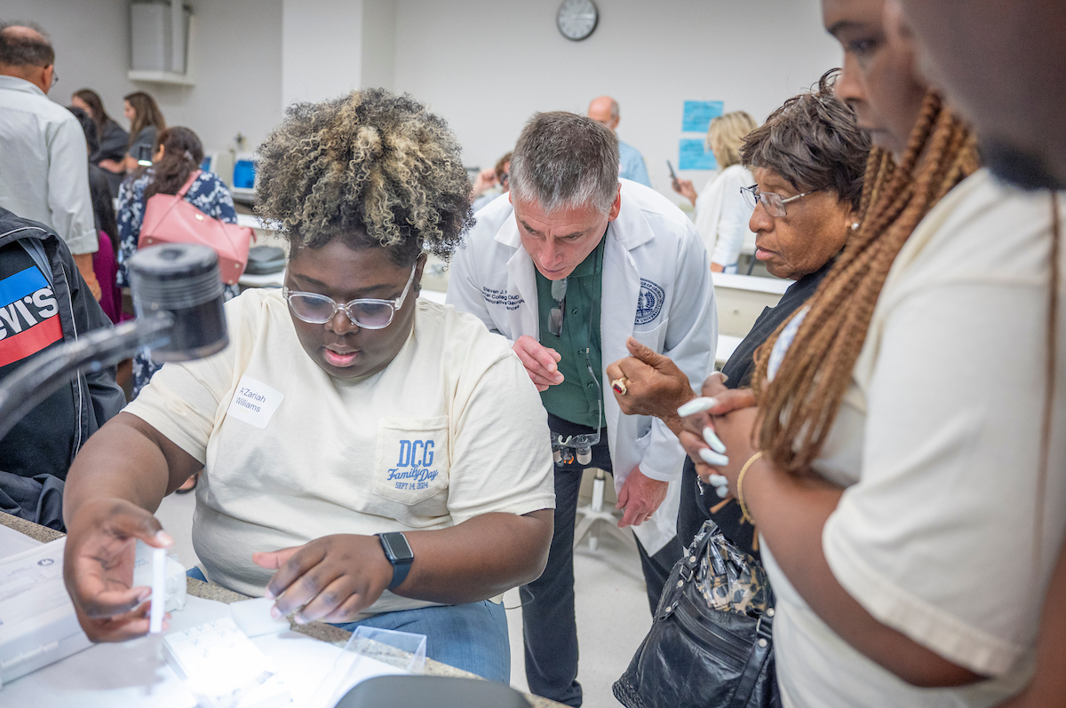 photo of professor observing dcg student looking through microscope