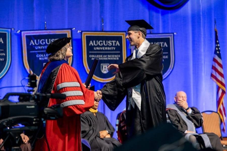 woman handing student diploma tube