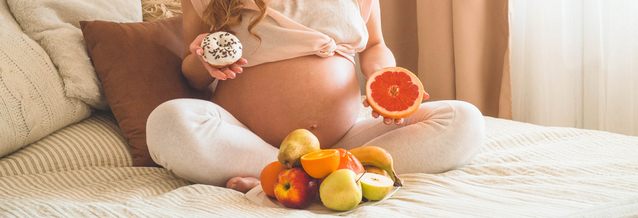 pregnant woman holding a donut and a grapefruit
