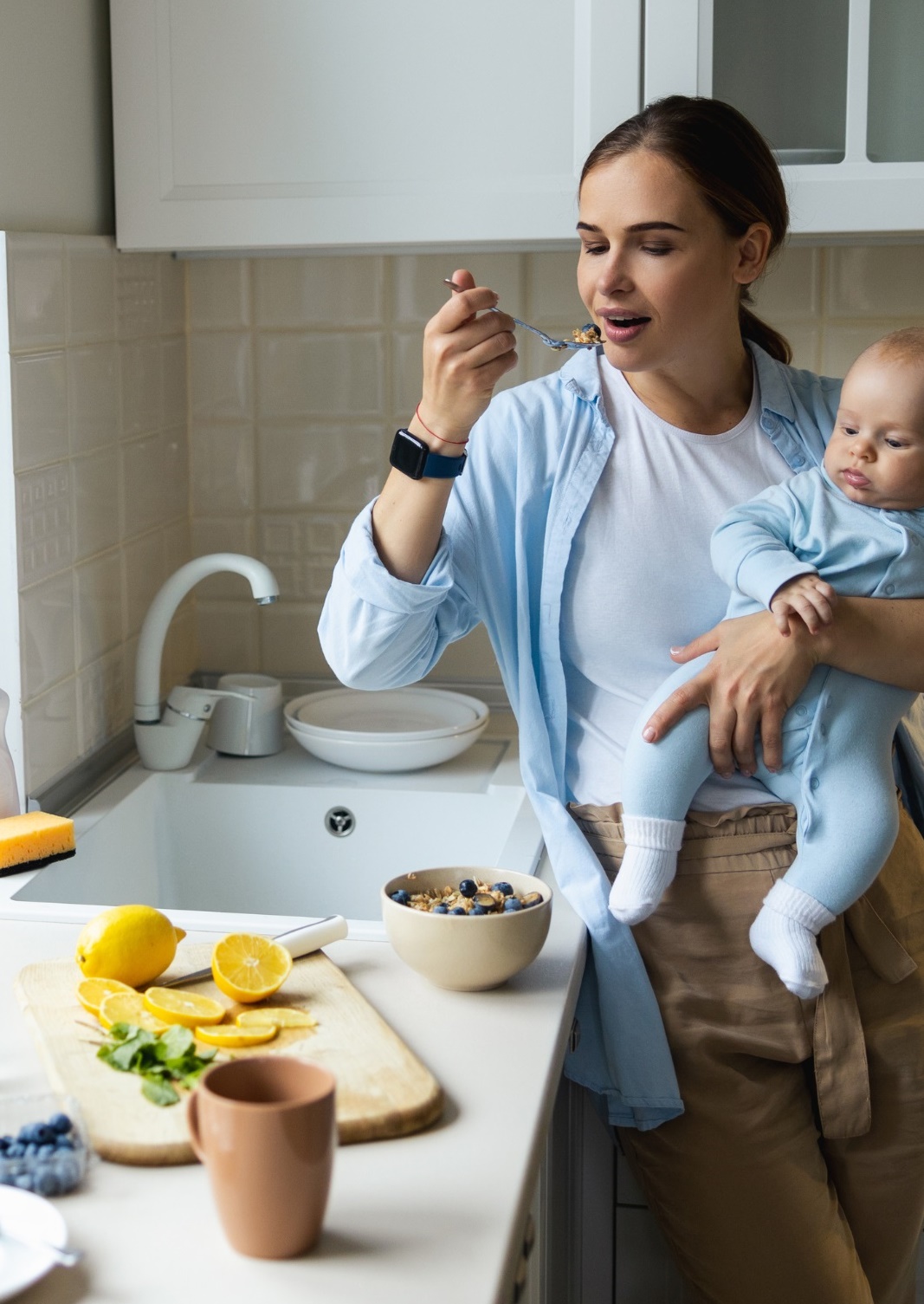 Mother holding baby eating breakfast parfait