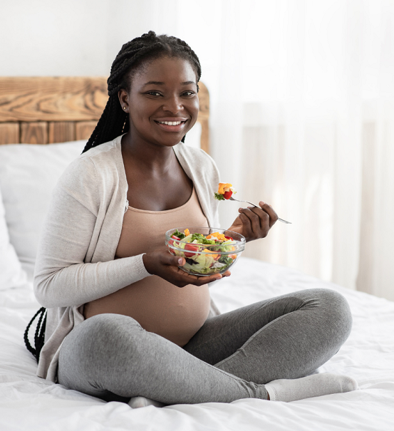 Woman enjoys a healthy salad on her bed