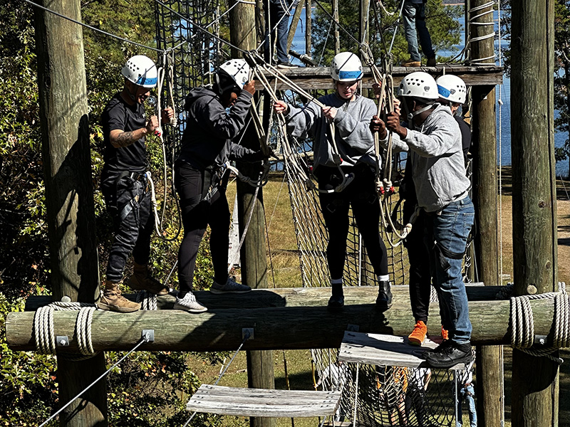 Cadets stand with helmets on as they navigate a high ropes course