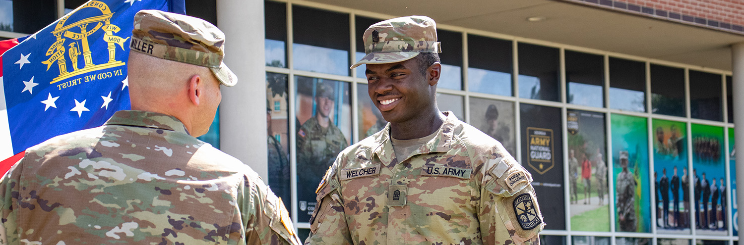 Cadet shakes commander’s hand in front of building