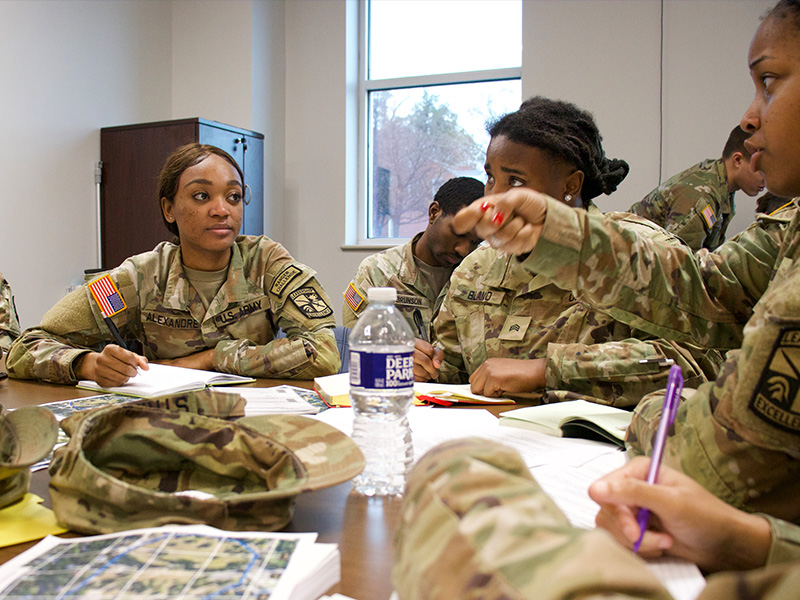 Cadets speak amongst themselves at a table with map across it