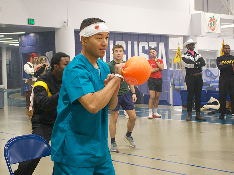 Cadet wearing a nurse costume holds a dodgeball during dodgeball event