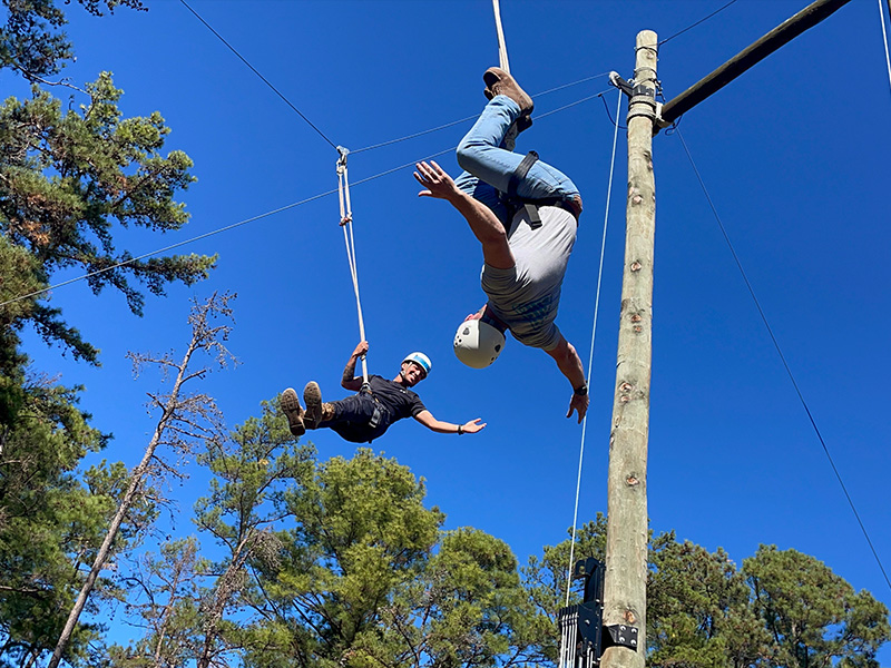 Cadets wave their arms as they descend on a zip-line