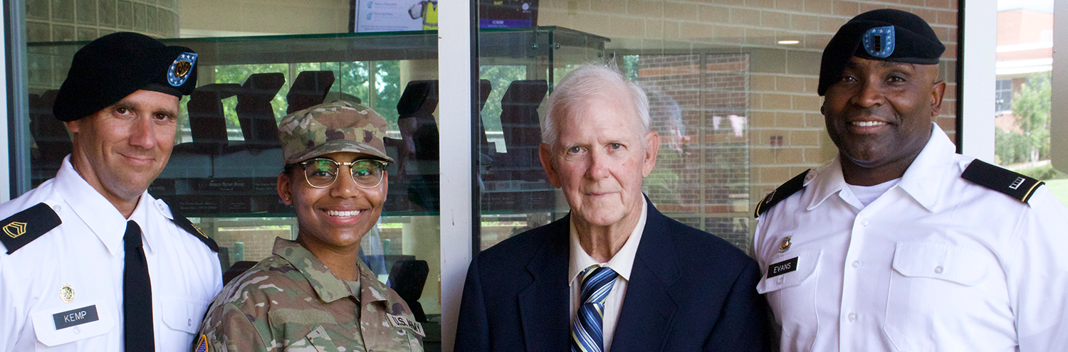 Cadet stands with gentlemen as they present a national scholarship