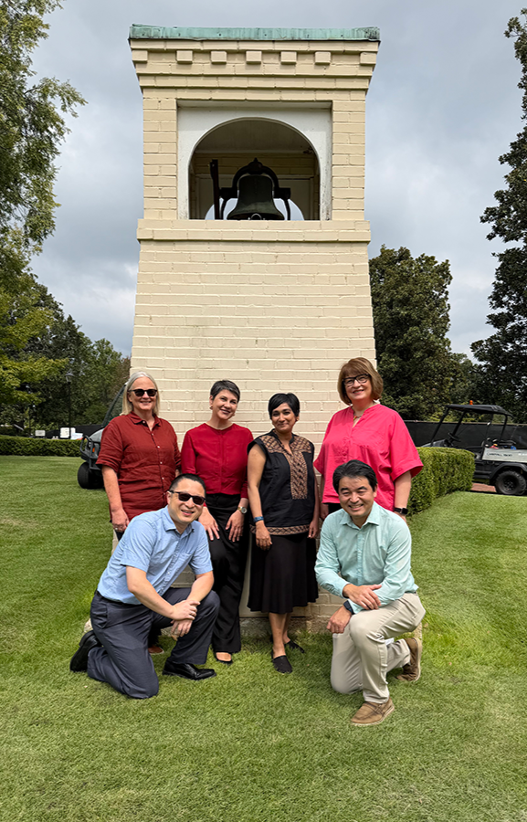 Teaching and Learning Team group of men and women standing and kneeling in front of a belltower
