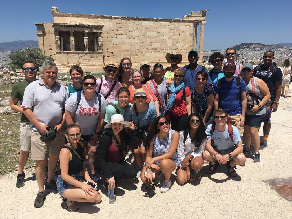 students posing in front of a grecian building