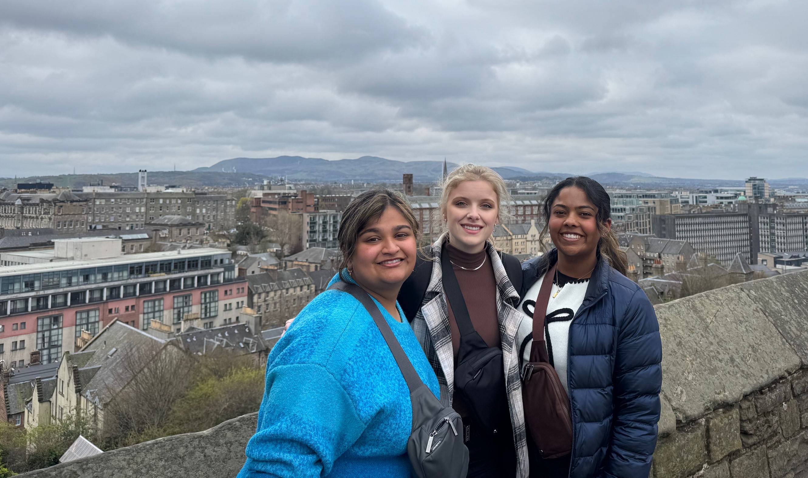 students standing atop a stone building with buildings in setting