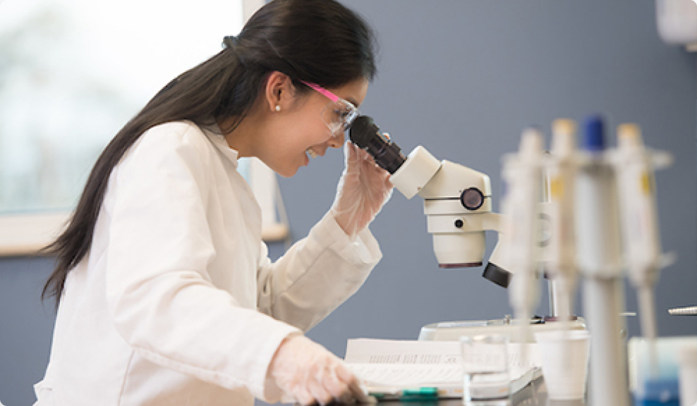 A graduate student looks into a microscope